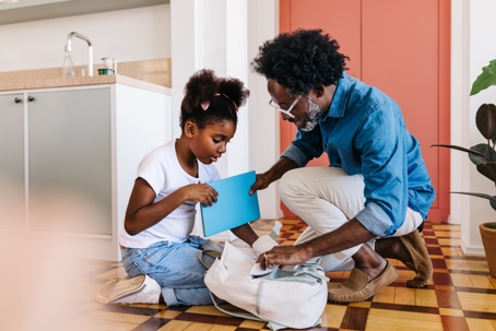 father helping daughter get ready for school
