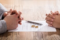 Folded hands over divorce papers Folded hands over divorce papers